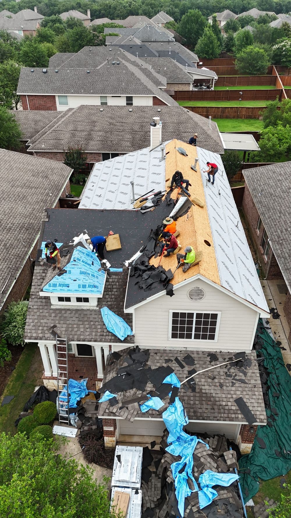 Roof replacement in progress with workers installing shingles on a residential home.