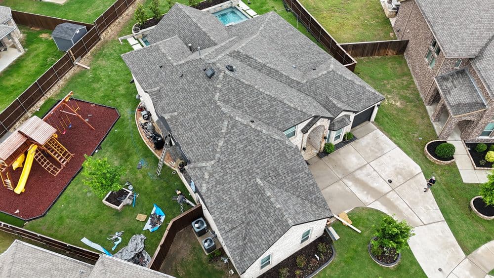 Aerial view of a home with a gray roof, landscaped yard, and playground equipment.