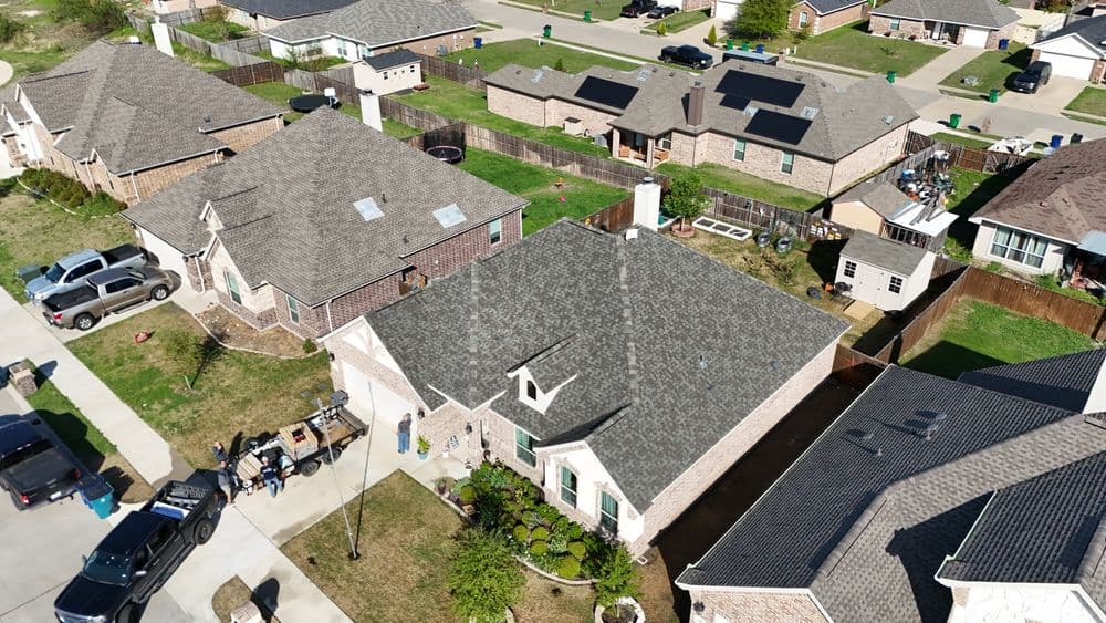 Aerial view of residential neighborhood with homes, solar panels, and green yards.