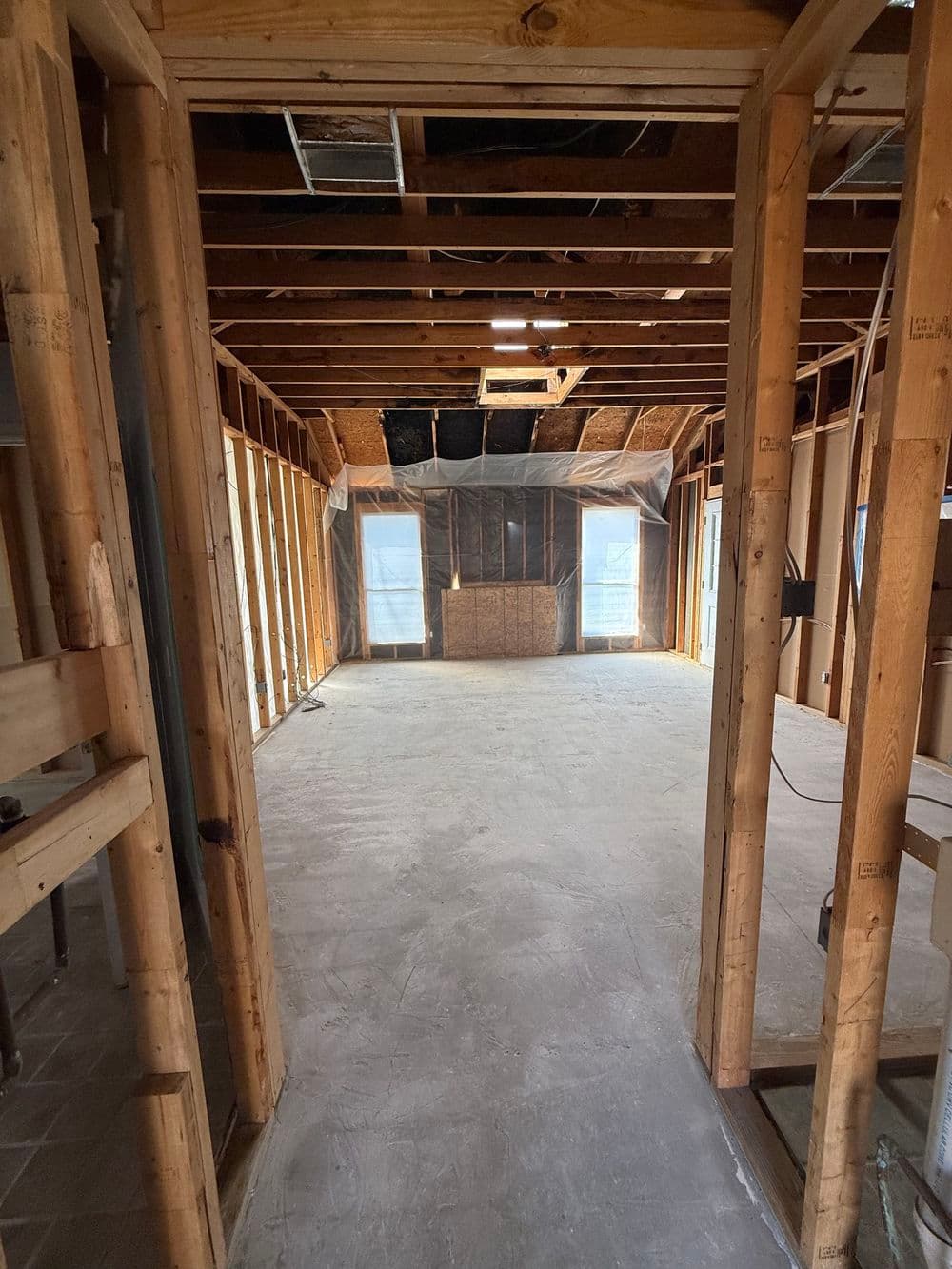 Interior view of a home under construction, showcasing exposed framing and unfinished flooring.