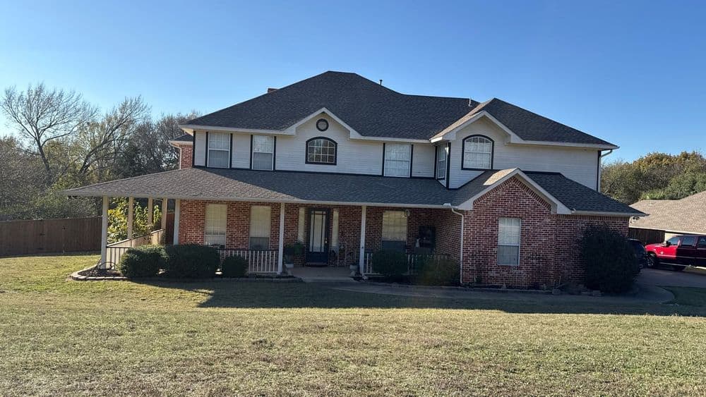 Two-story brick house with a front porch and large yard in a suburban setting.